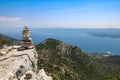 Stack pyramide of stones on top of mountain on background of mountains covered with forests and sea. Croatia, Bol island