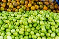 Stack of Raw Green fresh Monkey Apple or Indian Plum or Jujube and Orange in Market