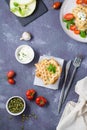 A stack of ready-to-eat zucchini waffles and basil on baking paper on the table. Vegetable dietary vegetarian food. Top and