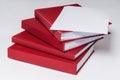 Stack of red hardcover books or reports with empty sheet of paper on the top, on white background. Royalty Free Stock Photo