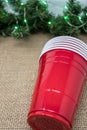 Stack of red party cups on a burlap background with Christmas garland. Concept for a Christmas party where alcohol is