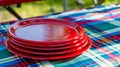 Stack of Red Plastic Plates on a Picnic Tablecloth. Generative ai Royalty Free Stock Photo