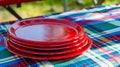Stack of Red Plastic Plates on a Picnic Tablecloth. Generative ai
