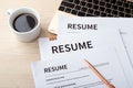 Stack of resumes on laptop with pen and coffee cup