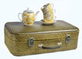 A stack of retro cups and a ceramic teapot on old leather suitcase isolated on a white background. Royalty Free Stock Photo