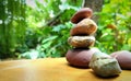 Stack of river stones arrange on the table with beautiful green garden background look fresh and beautiful.