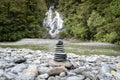 Stack of rocks, cairn, positioned on a pebble beach in front of big waterfall , New Zealand Royalty Free Stock Photo
