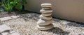 A stack of rocks in the graveled area, near a wall and a potted plant Royalty Free Stock Photo