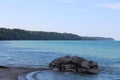 Stack of rocks on the lakeshore with clear blue water and green forests in the background Royalty Free Stock Photo