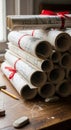 Stack of rolled architectural blueprints tied with red ribbons on a wooden table. The plans display Royalty Free Stock Photo