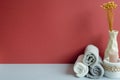 Stack of rolled shower cotton towels and candle, vase of dry flower. bathroom spa concept. red and gray background Royalty Free Stock Photo