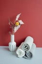 Stack of rolled shower cotton towels and vase of dry flower. bathroom spa concept. red and gray background Royalty Free Stock Photo