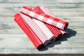 Stack of rolled up red white checkered and striped linen tableclothes on rustic bright wooden table.Outdoor. Royalty Free Stock Photo