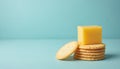 Stack of round salty crackers with yellow cheese cube on top. Simple food appetizer snack isolated on plain blue background. Royalty Free Stock Photo