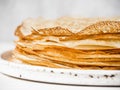 Stack Russian homemade thin pancakes on white plate on wood background. Traditional wheat pancakes for Shrovetide