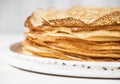 Stack Russian homemade thin pancakes on white plate on wood background. Traditional wheat pancakes for Shrovetide