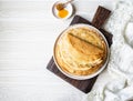 Stack Russian homemade thin pancakes on white plate and wood honey spoon and honey on small white plate. Traditional wheat