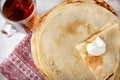 Stack of Russian pancakes on a plate, a mug of black tea sour cream, sauce, top view,  on a towel with a red pattern on a white Royalty Free Stock Photo