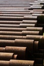 Stack of rusty brown hollow iron pipes for drilling for oil, natural gas or groundwater