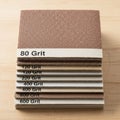 A stack of sandpaper sheets is neatly arranged on a wooden surface Royalty Free Stock Photo