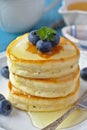 A stack of scotch pancakes with with honey and blueberries on a breakfast table Royalty Free Stock Photo