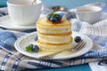 A stack of scotch pancakes with with honey and blueberries on a breakfast table Royalty Free Stock Photo