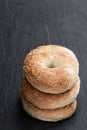 Stack of sesame seed bagels isolated on black stone background