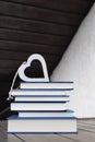 stack of several books and a heart on top of them on a table on a light and dark background Royalty Free Stock Photo