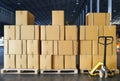 Stack of shipment package boxes on wooden pallets and hand pallet truck in interior warehouse storage.
