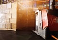 Stack of shipments boxes on wooden pallets and Electric forklift pallet jack at the warehouse storage.