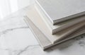 Stack of six clothbound books on marble surface. White, gray, brown books in pyramid formation. Neatly arranged, visually Royalty Free Stock Photo