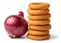 A stack of six golden, crispy onion rings is placed beside a whole red onion (Allium Royalty Free Stock Photo