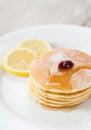 Stack of small pancakes with honey and lemon