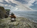 Stack of small rocks on a big stone, beautiful ocean scene in the background with cloudy sky. Relaxation and zen concept Royalty Free Stock Photo