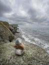 Stack of small rocks on a big stone, beautiful ocean scene in the background with cloudy sky. Relaxation and zen concept Royalty Free Stock Photo