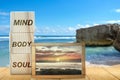 Stack of small wooden cubes with the text of mind, body, and soul with a small chalkboard with a view of the sunset scene on the Royalty Free Stock Photo