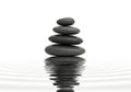 Stack of smooth dark stones balanced perfectly on rippling water isolated on white background Royalty Free Stock Photo