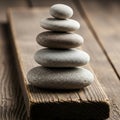 A stack of smooth, flat stones arranged in ascending size on a wooden plank. The Royalty Free Stock Photo