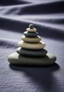 A stack of smooth, flat stones is arranged on a textured, dark fabric surface. The stones Royalty Free Stock Photo