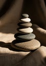 A stack of smooth, flat stones is arranged vertically, balancing precariously on a textured Royalty Free Stock Photo