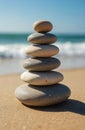 Stack of smooth pebbles on sandy beach with ocean waves in background. Balanced stones suggest harmony, peace, and nature. Ideal Royalty Free Stock Photo