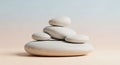 Stack of smooth, rounded, light gray pebbles balanced on a light peach colored surface with a soft gradient background Royalty Free Stock Photo