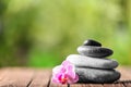 Stack of spa stones and beautiful flower on wooden table against blurred background Royalty Free Stock Photo