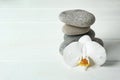 Stack of spa stones and beautiful orchid flower on white table Royalty Free Stock Photo