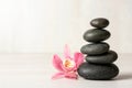 Stack of spa stones and flower on table against white background Royalty Free Stock Photo