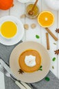 Stack of spicy pumpkin pancakes on a plate with honey and whipped cream on a white wooden background. Royalty Free Stock Photo