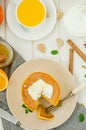 Stack of spicy pumpkin pancakes on a plate with honey and whipped cream on a white wooden background. Royalty Free Stock Photo