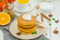 Stack of spicy pumpkin pancakes on a plate with honey and whipped cream on a white wooden background. Royalty Free Stock Photo