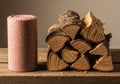 A stack of split firewood with rough bark is neatly arranged on a wooden surface. Next to the wood, Royalty Free Stock Photo
