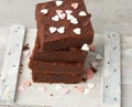 Stack of square baked brownie chocolate cake slices on a white background